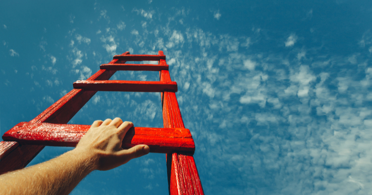 A man climbing up a ladder pointing to the sky representing scaling trade busiensses through training
