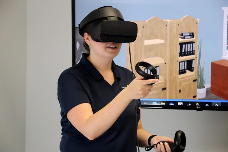 A woman wearing a VR headset for a 3D simulation service team trainig course that uses visual baselining
