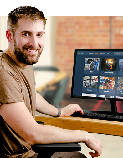 A man sitting at a desk infront of a computer viewing Interplay's online skilled trades courses