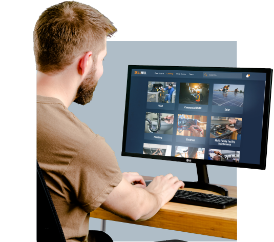 A man sitting at a desk using a computer for skilled trades training