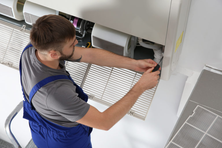 An HVAC technician working on an ac unit while practicing HVAC safety basics