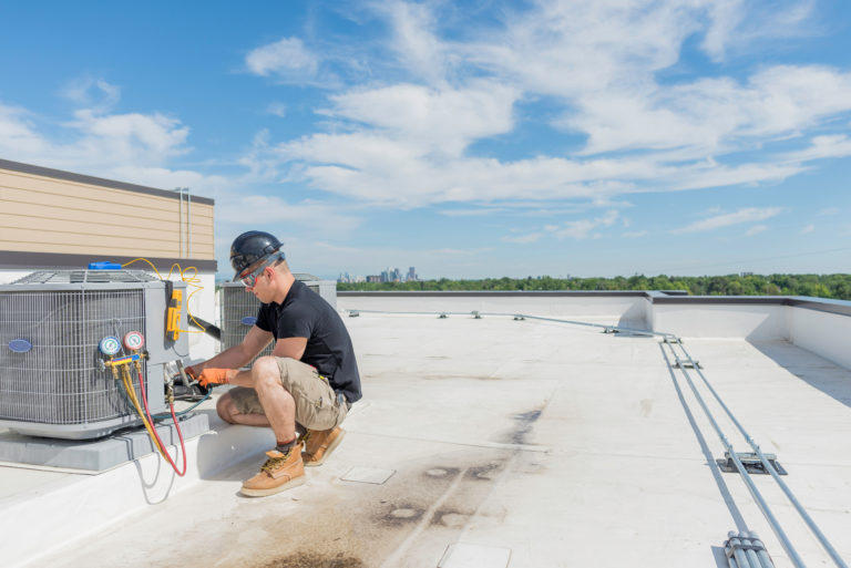A man working on an air conditioner on a roof