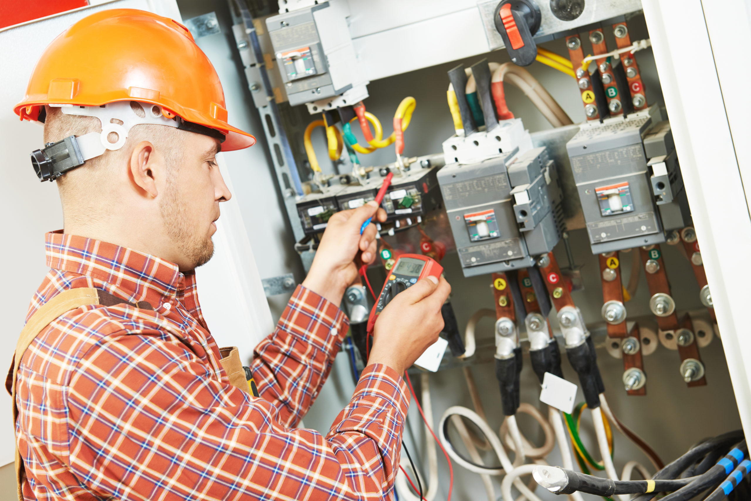 A man in a hard hat working on an electrical panel