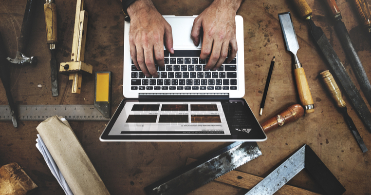 A man working on a laptop surrounded by tools