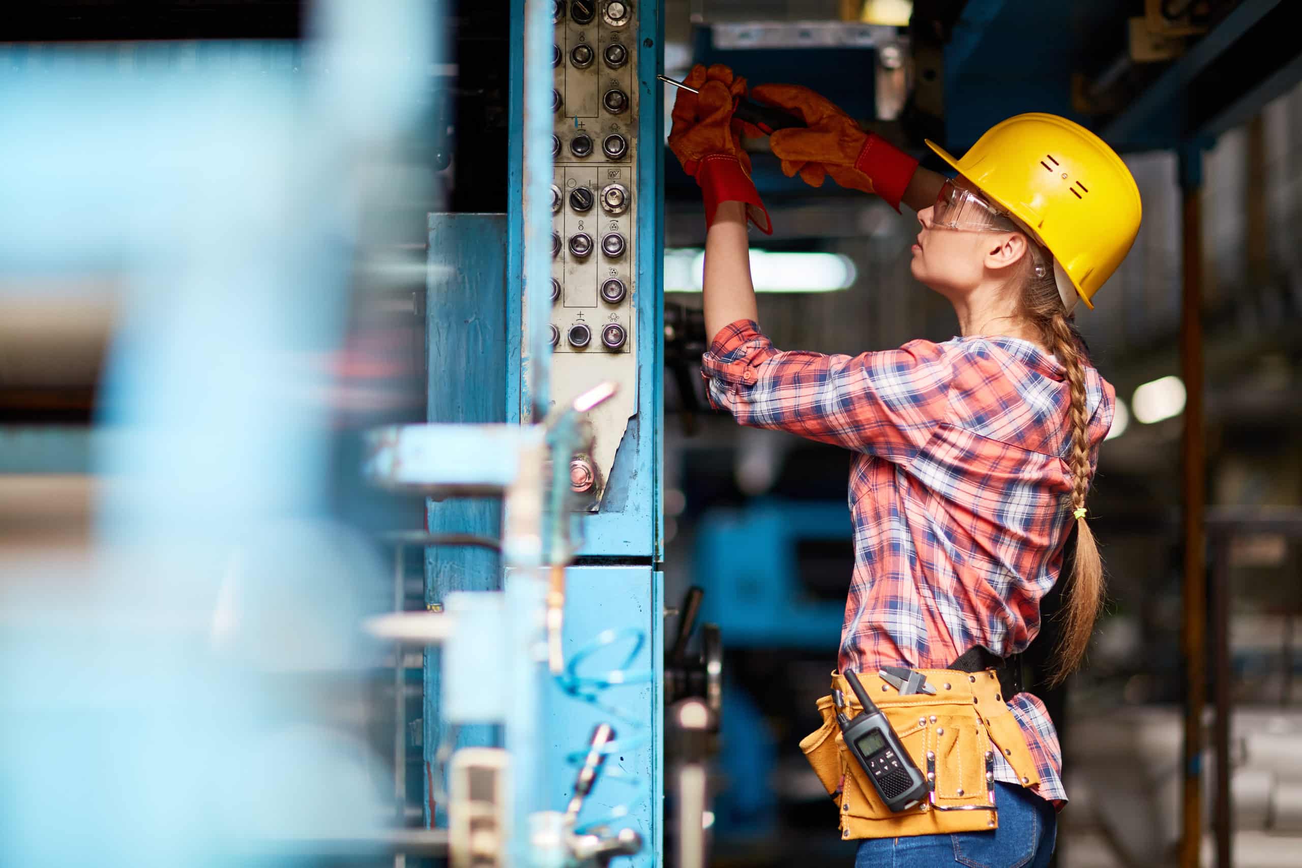 A woman in a hard hat working on a machine
