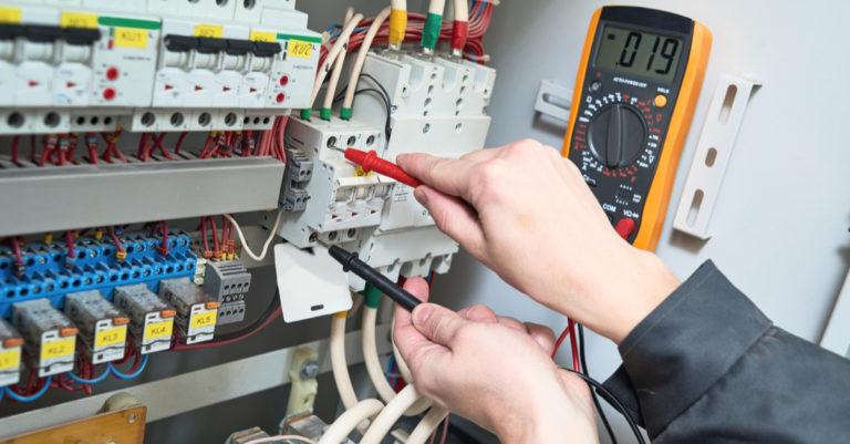 A man with an electrician apprentice job working on an electrical panel