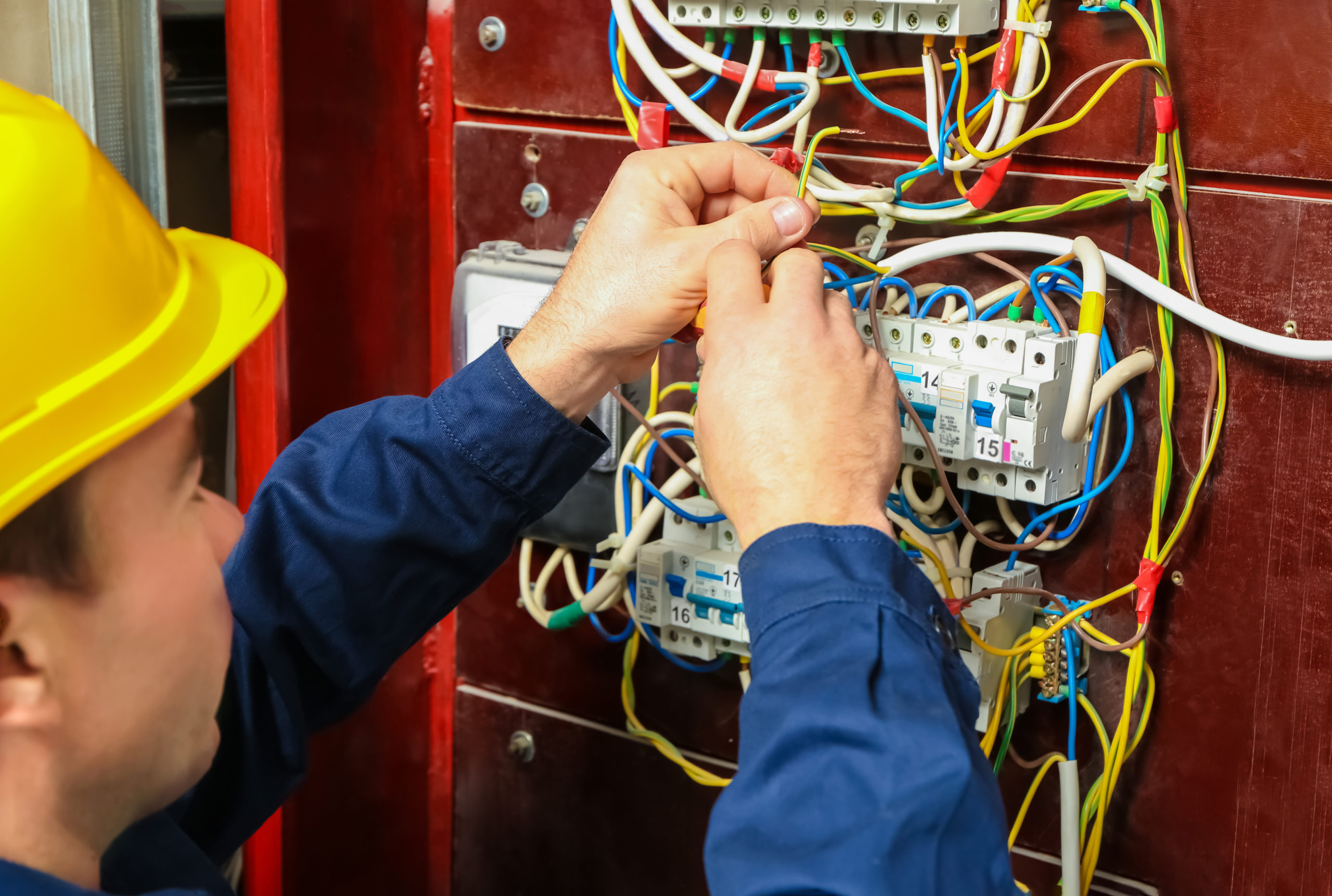 A man in a hard hat working on an electrical panel