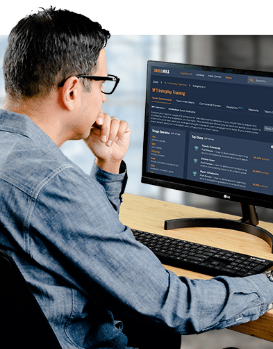 A man sitting at a desk in front of a computer looking at SkillMill's dashboard features
