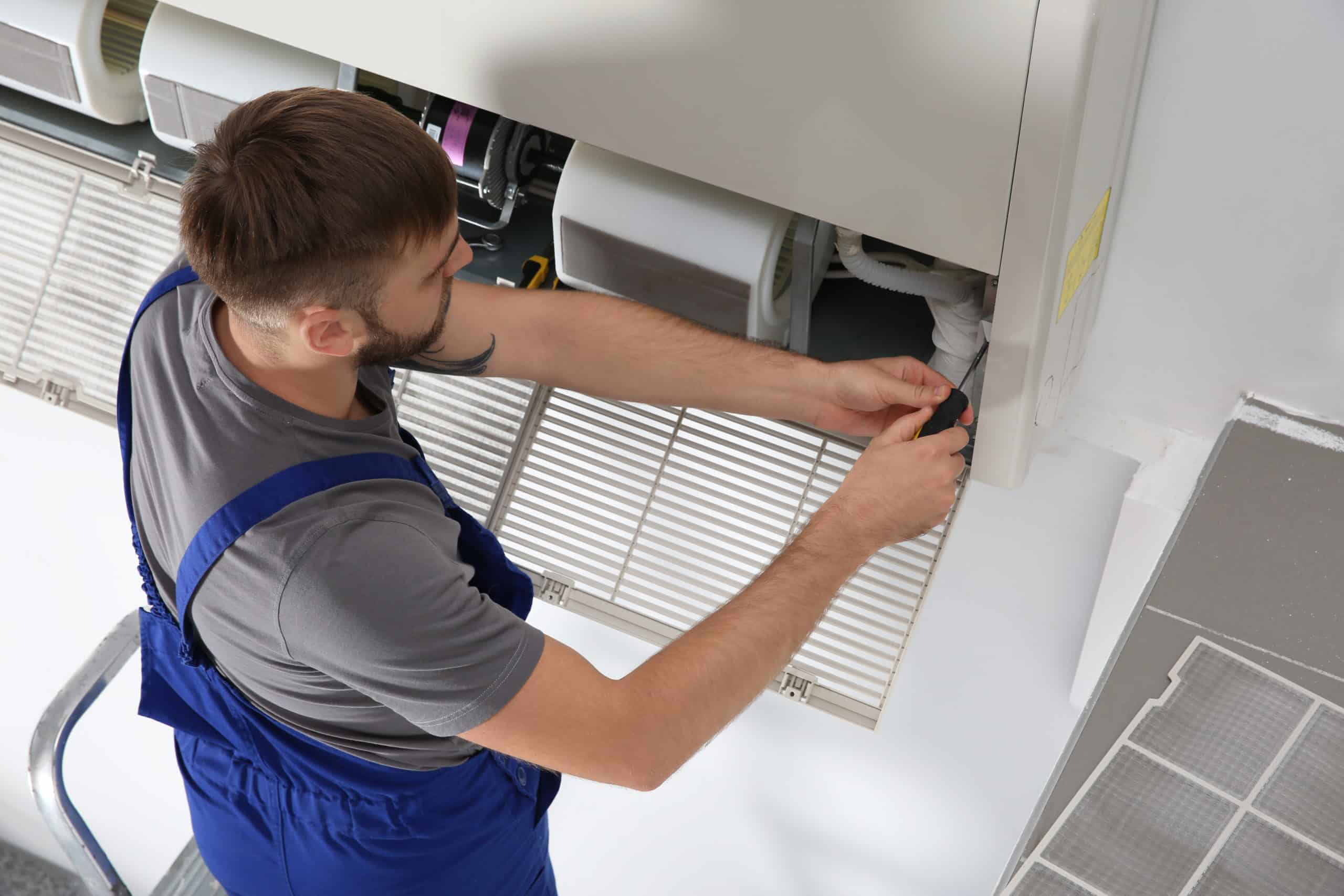 A man fixing an air conditioner in a room while using HVAC safety basics