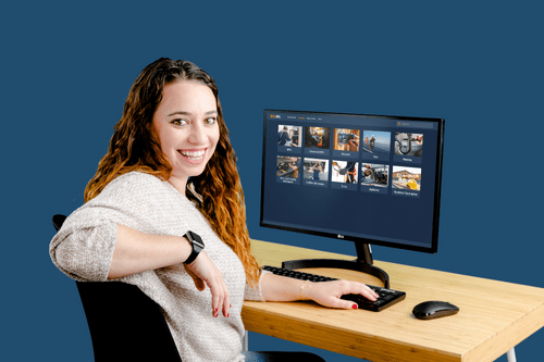 A woman sitting in front of a computer monitor that displays Interplay Learning's skilled trades training course catalog