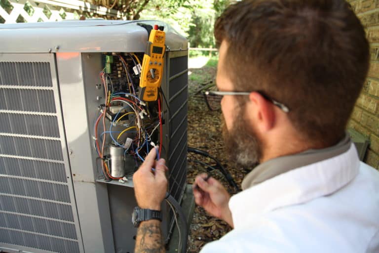 A HVAC business owner working on a unit outside