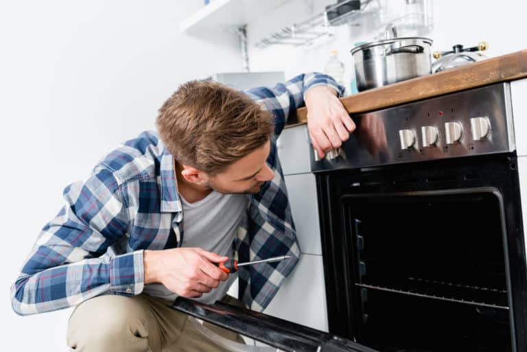 A property management technician fixing an oven in an kitchen