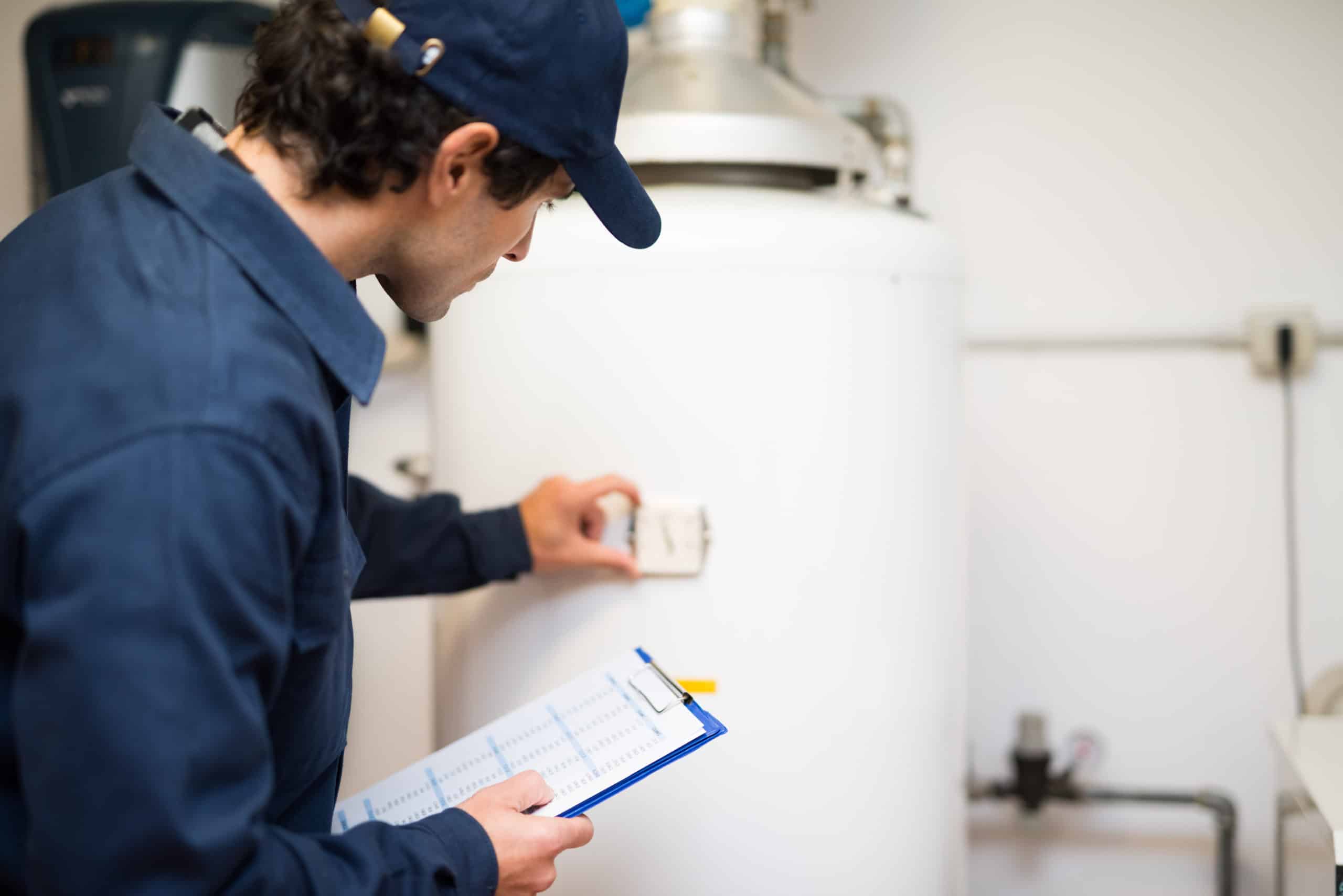 A man in a blue shirt checking a water heater that has undertgone hostipality training