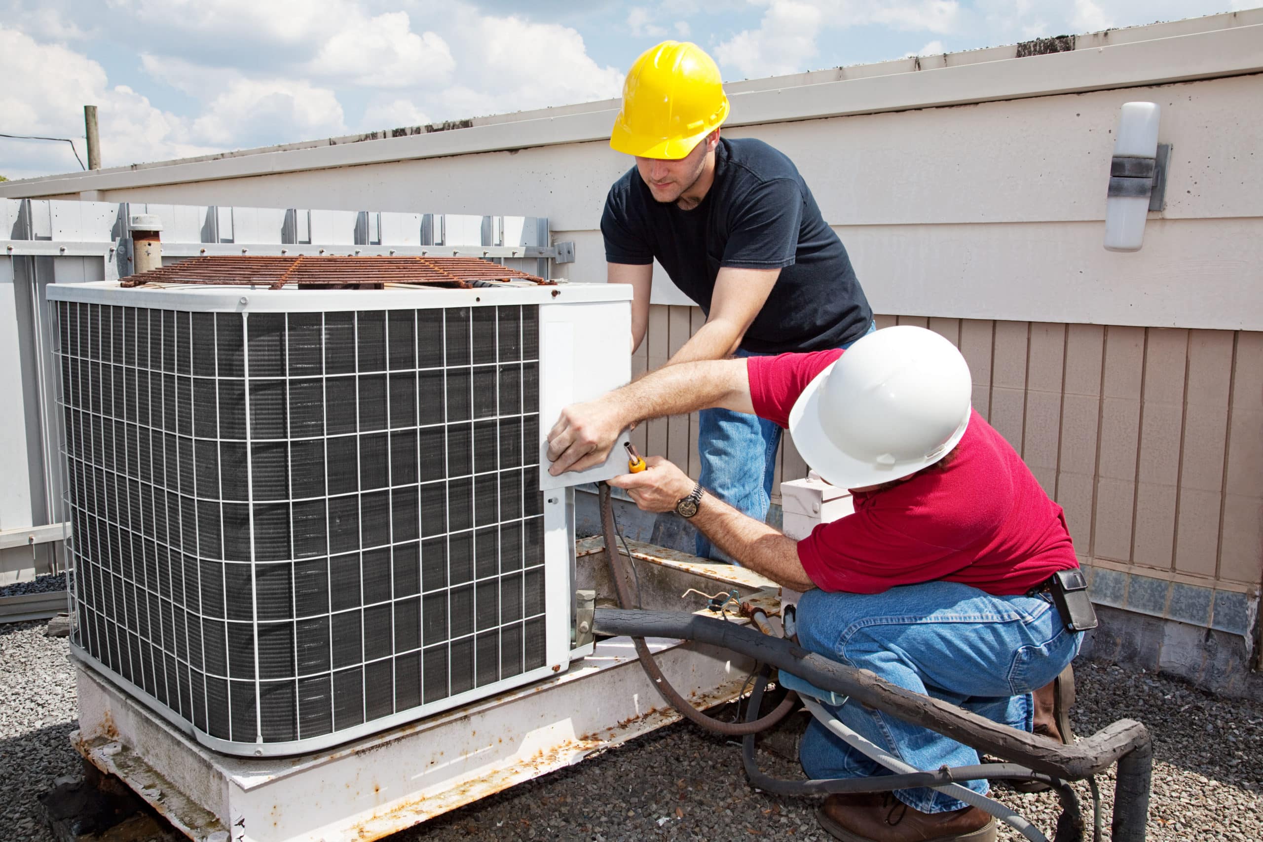 A couple of men working on an air conditioner