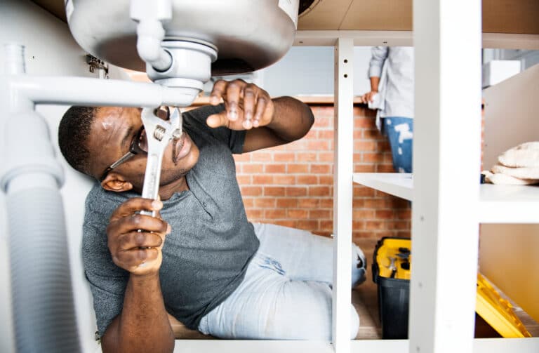 A plumber using a wrench to fix a sink