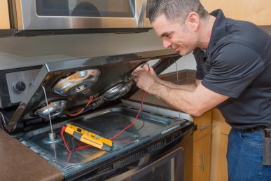 A multi-family maintenance technician fixing an oven in a kitchen