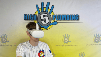 a man wearing a virtual reality headset in front of a high 5 plumbing sign
