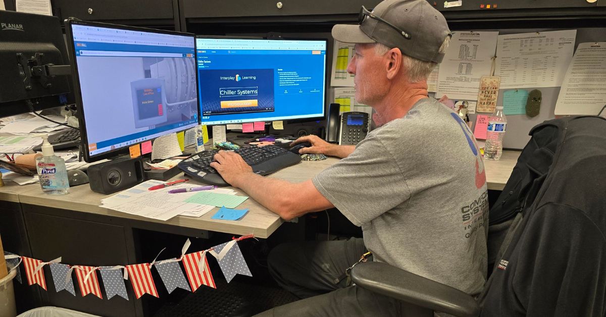 a man sitting at a desk with two computer monitors
