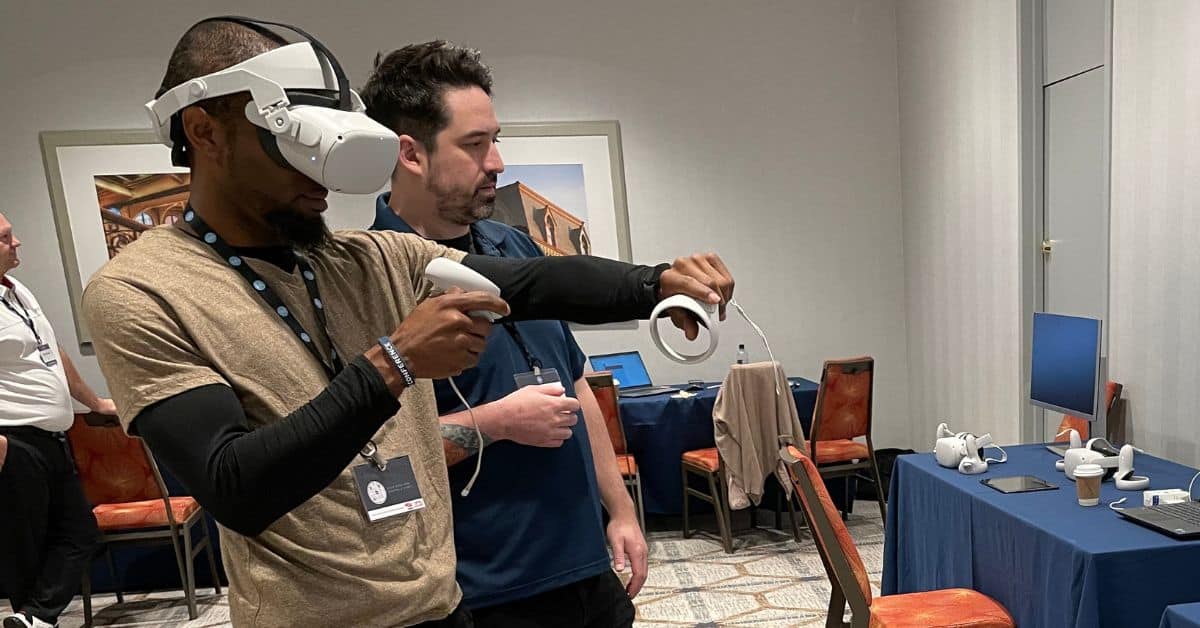 two men standing next to each other holding virtual reality training controllers