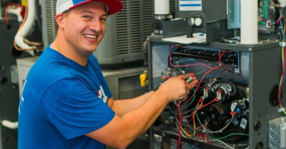 a man in a blue shirt is working on an air conditioner