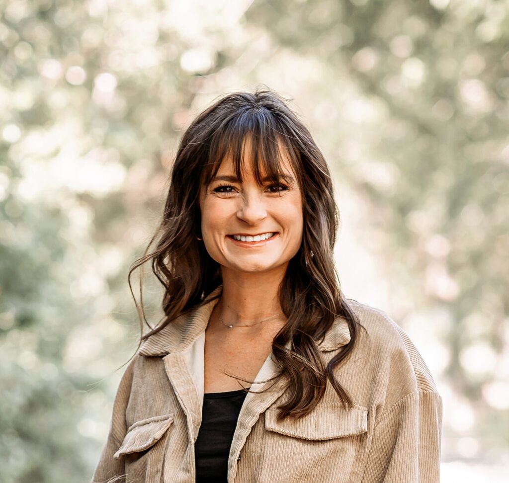 a woman in a tan jacket smiles at the camera